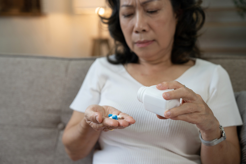 An Asian Woman Dumping Pills Into Her Hand from A Bottle Senior Medication Management Tips